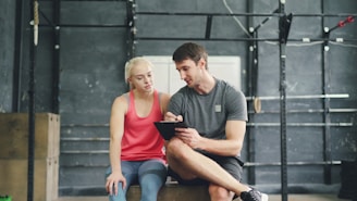 Trainer discusses progress with client using tablet in gym.