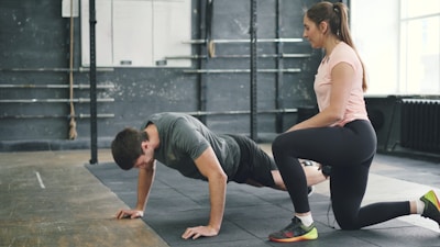 Man doing push-ups with a trainer spotting him.