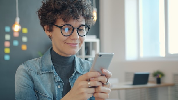 Woman smiling while looking at her smartphone