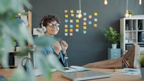 Young woman with headphones happily working at desk.