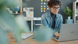 A woman with curly hair working on a laptop.