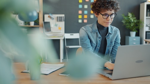 A woman with curly hair working on a laptop.