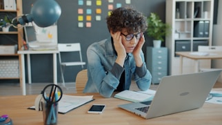 A person looking stressed at a laptop in an office.