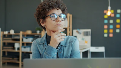 Woman wearing glasses thinking at desk
