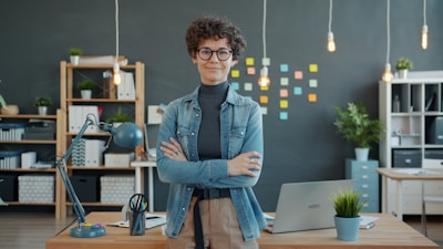 A woman smiles with arms crossed in an office.