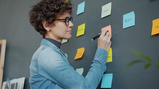 Woman writing on colorful sticky notes on wall