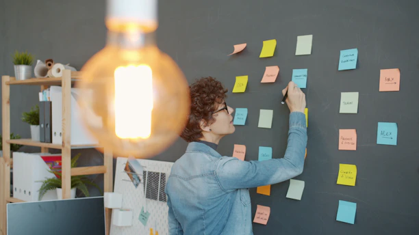 Person writing on colorful sticky notes on wall