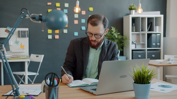 Man working at desk with laptop and notebook.