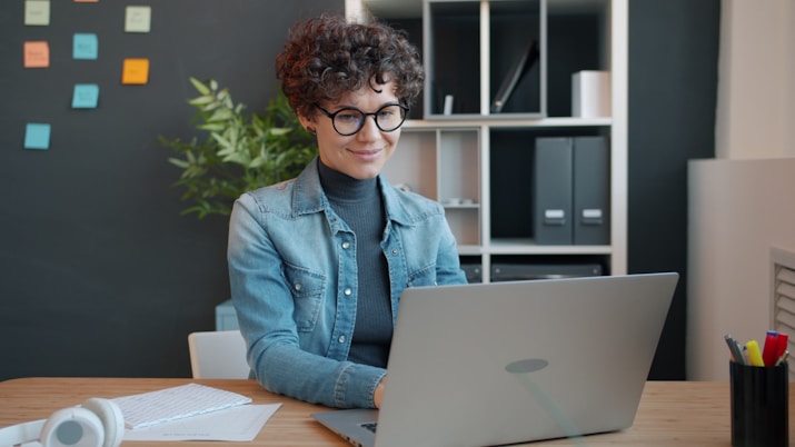 Woman working on a laptop at a desk.