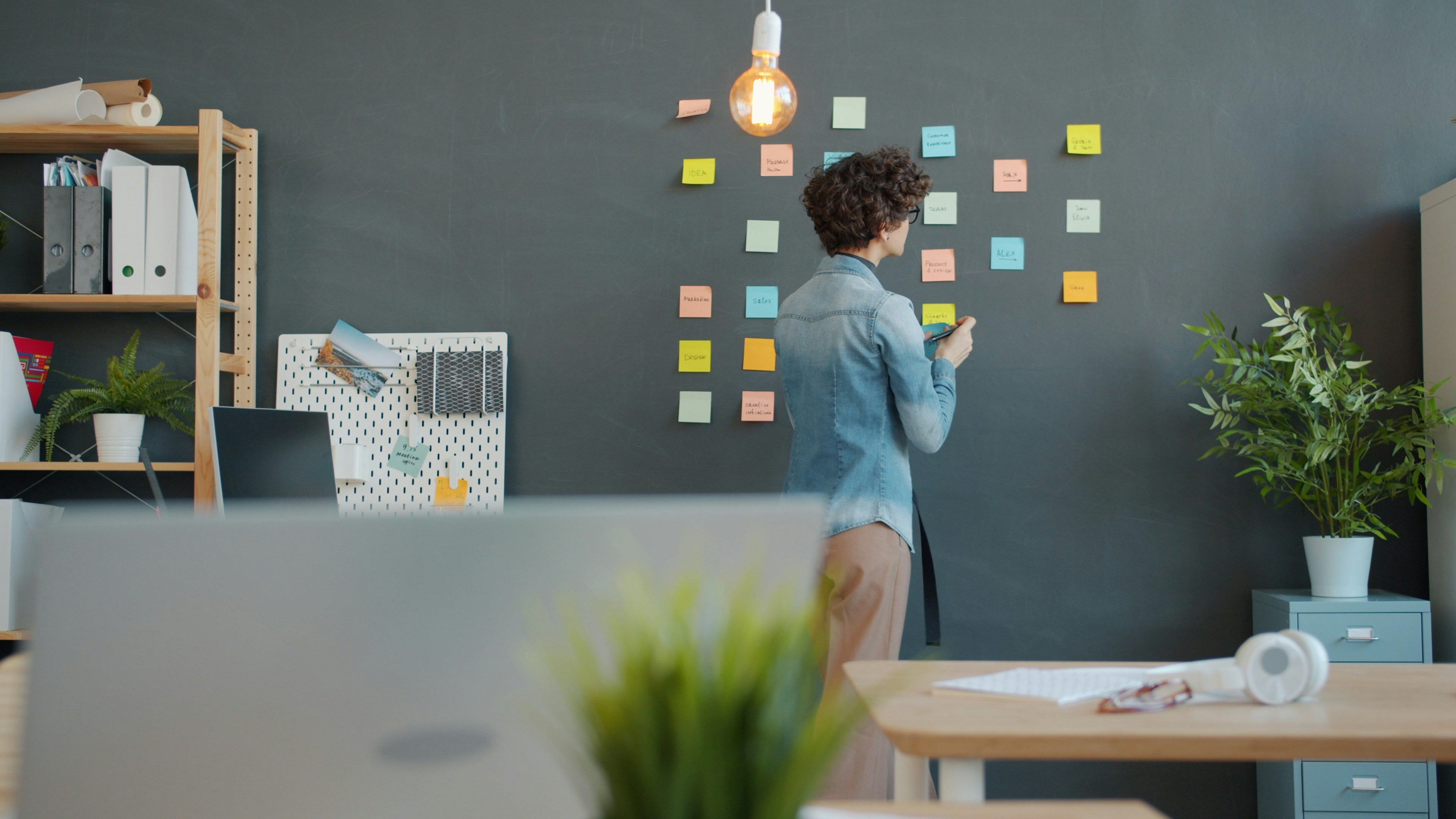Woman adding sticky notes to a dark wall
