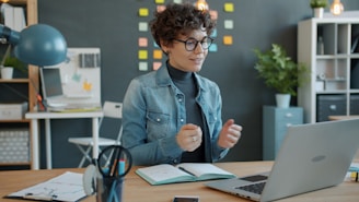 Woman gesturing while on a video call at desk.