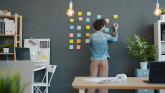 Woman writing on sticky notes on a wall.