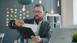 Man in glasses reviewing documents at desk