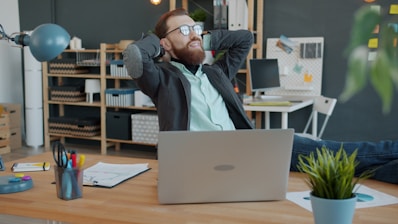 Man relaxing at his office desk with laptop.