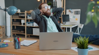 Man relaxing at his office desk with laptop.