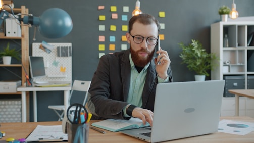 Man on phone working on laptop in office