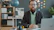 Man with beard and glasses sitting at desk