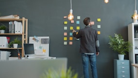 Man planning on sticky notes wall in office