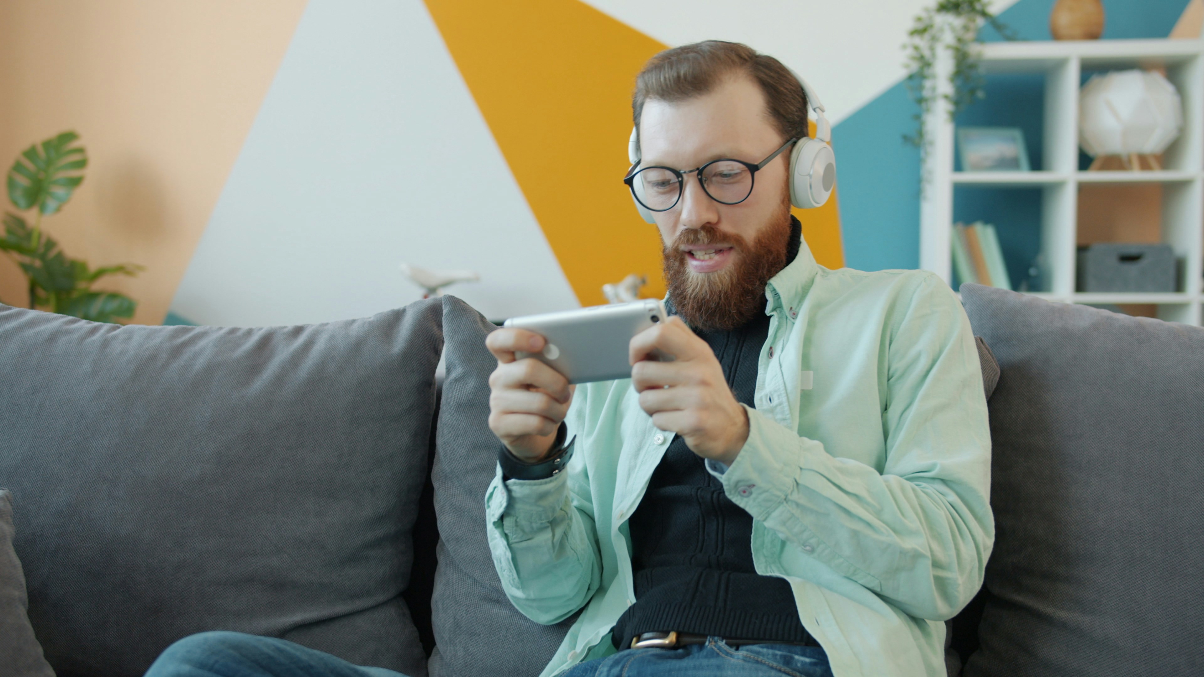 Man with headphones playing game on smartphone