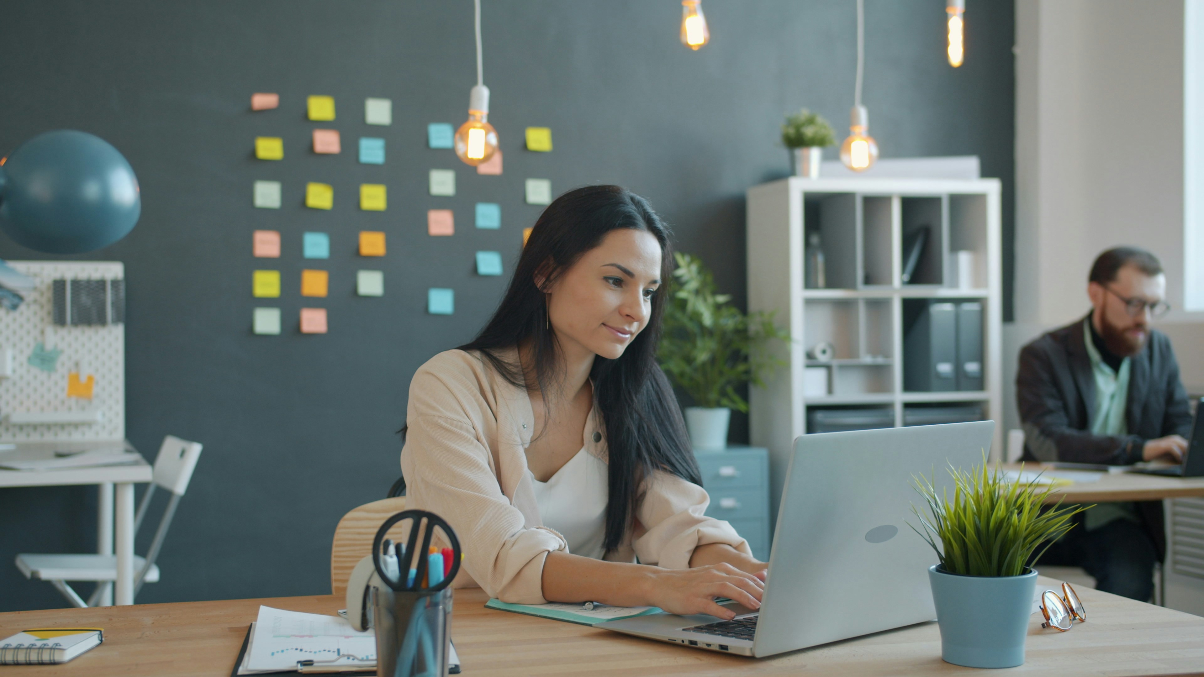 Young woman is working with laptop in creative shared office typing