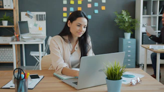 Woman working on a laptop at an office desk.