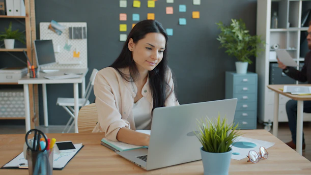 Woman working on a laptop at an office desk.