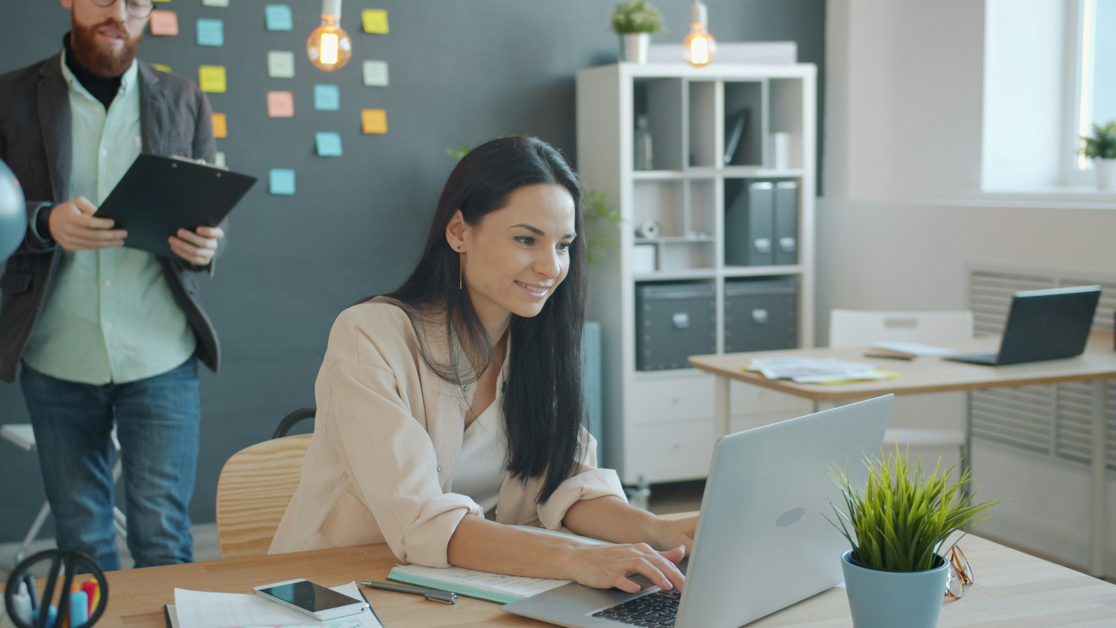 Businessman and businesswoman discussing business document in creative office talking looking at paper, woman is using laptop typing. People and job concept.