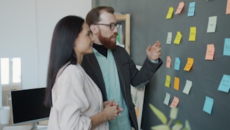 Two colleagues discussing ideas on a sticky note board.