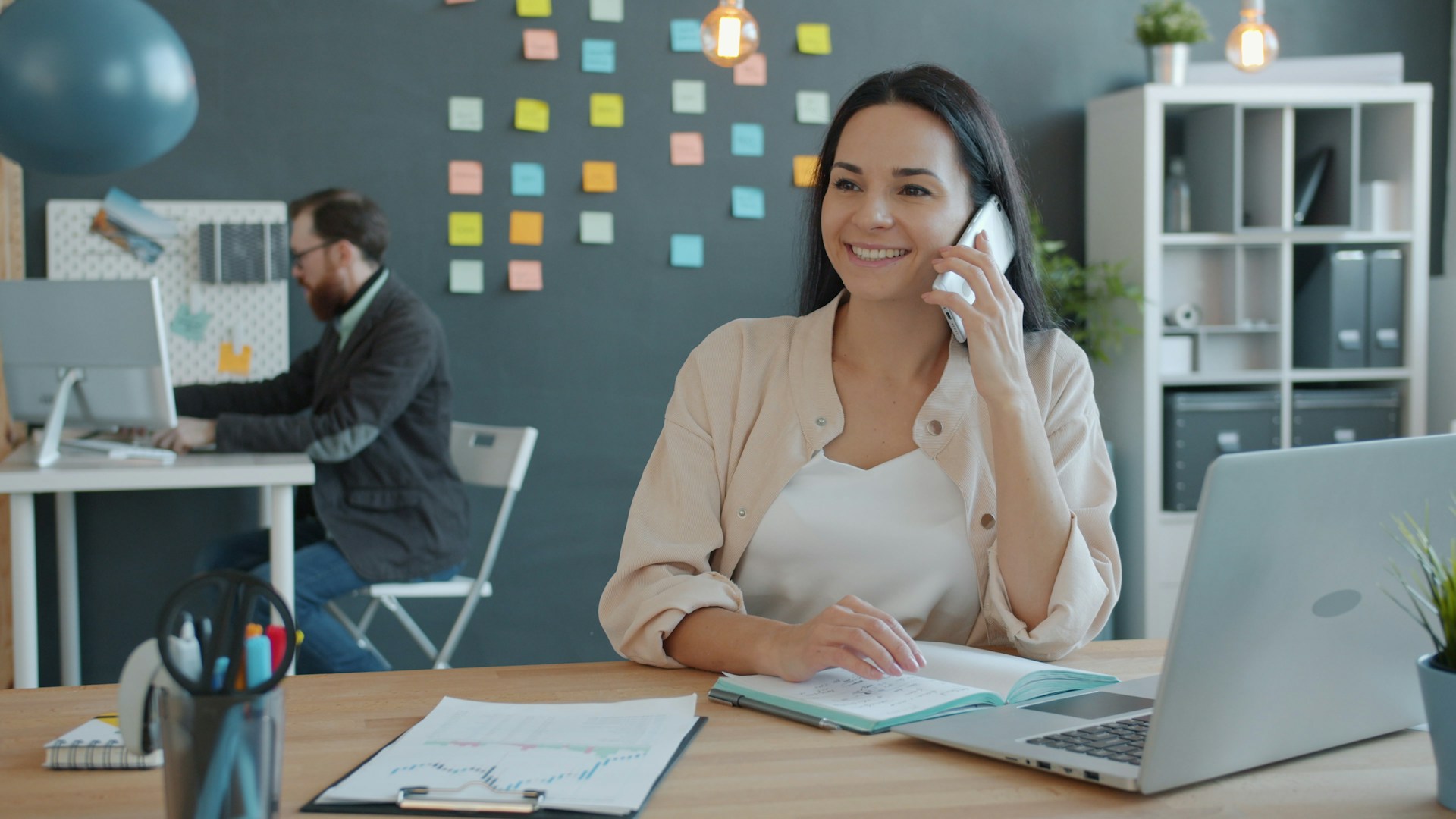 Woman talking on phone at desk with laptop