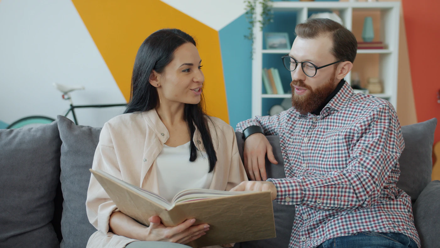 Couple looking through a photo album as a personalized six month anniversary gift