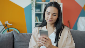 A woman looking at her smartphone on a couch.
