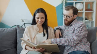 Couple looking at a photo album together on couch.