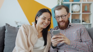 Couple laughing while looking at a smartphone together.
