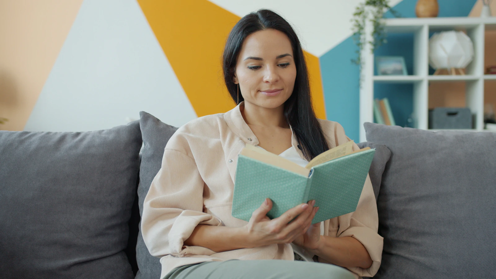 Woman reading alone on a sofa, representing healthy personal space and independent time in a relationship