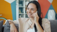 A woman smiling while talking on a cell phone.
