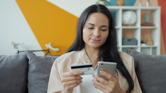 Woman holding credit card and phone for online shopping.
