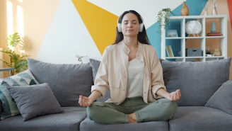 Woman meditating on couch with headphones on