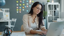 Young woman working on laptop in modern office.