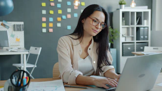 Young woman working on laptop in modern office.