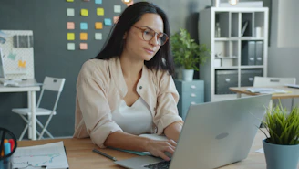 Woman working on laptop in modern office setting.