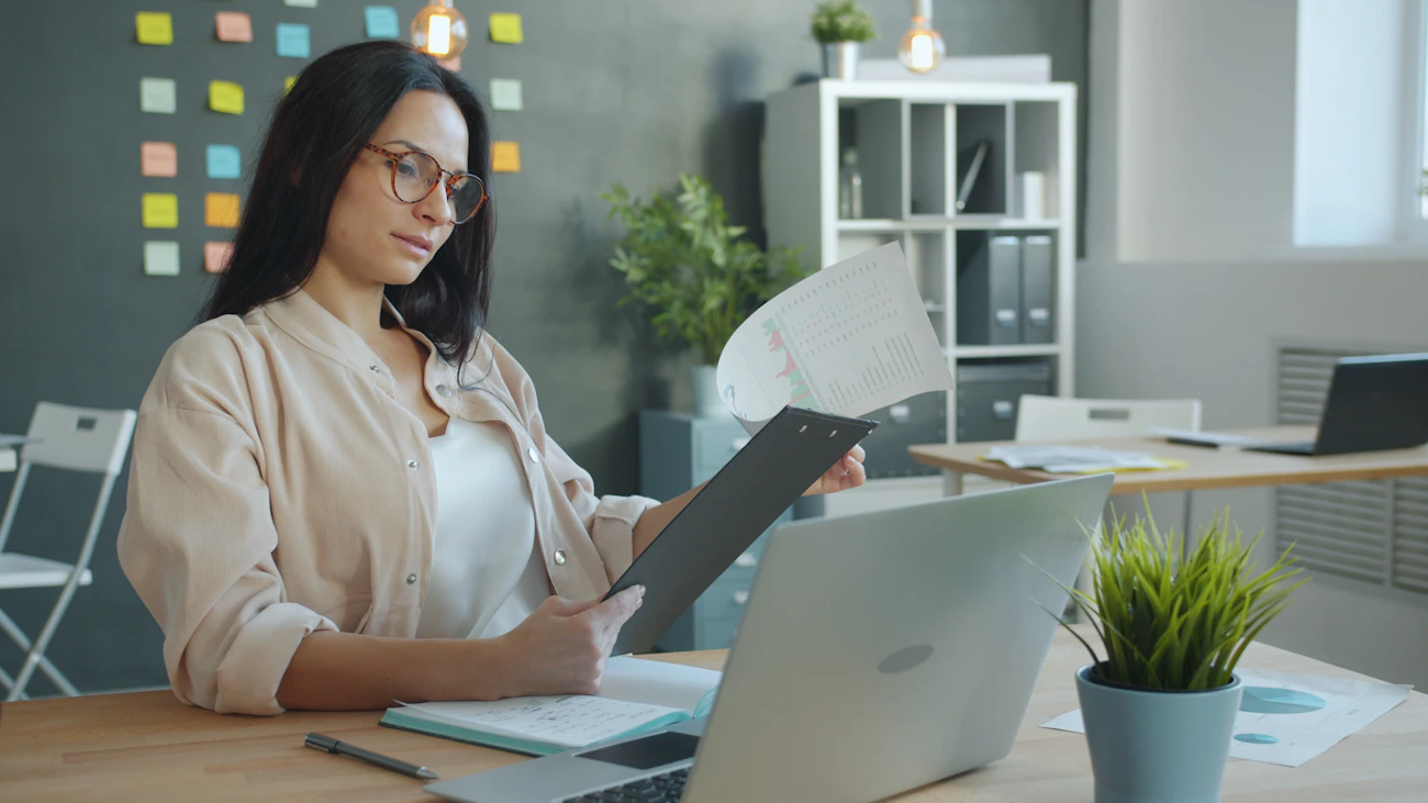 Professional reviewing information and documents at a laptop