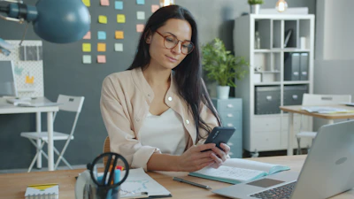Woman working on a smartphone at her desk.