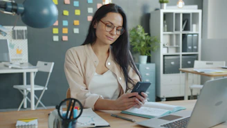 Woman working on a smartphone at her desk.