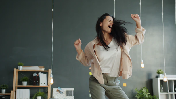 A woman joyfully dancing with arms raised