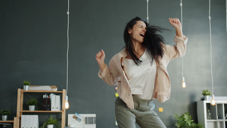 A woman joyfully dancing with arms raised.