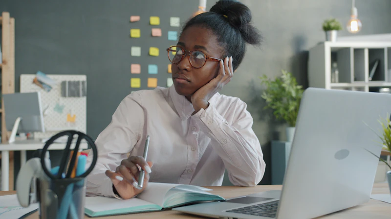 Office worker slouched at her desk, resting her head in her hand from fatigue and tension