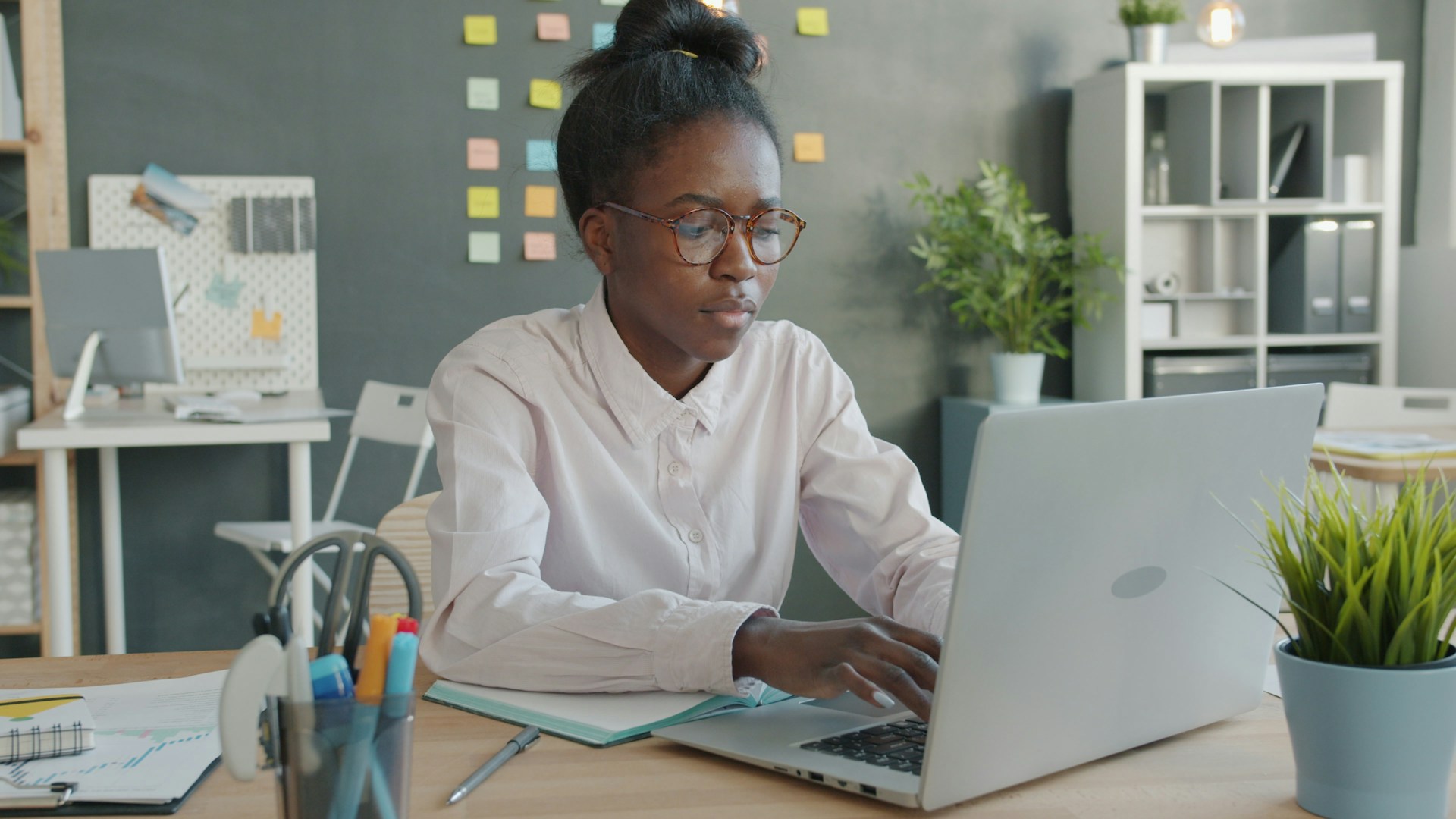A woman working on a laptop in an office.