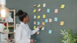 Woman points at colorful sticky notes on wall