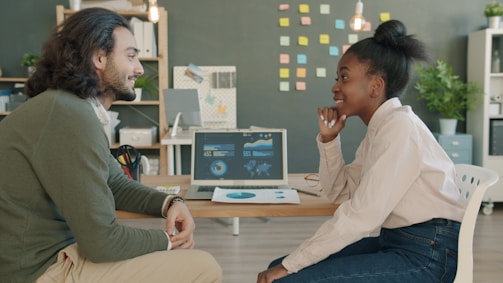Two colleagues discussing work at a desk.