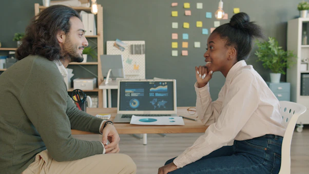 Two colleagues discussing work at a desk.